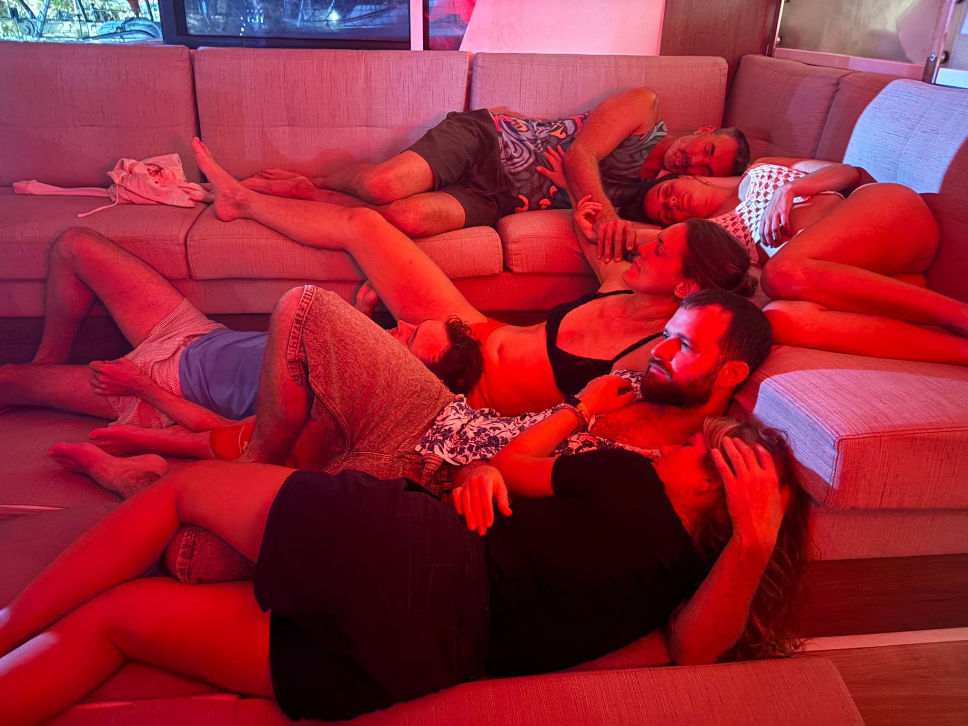 Guests relaxing together on the sofa in the yacht's salon under warm red evening light